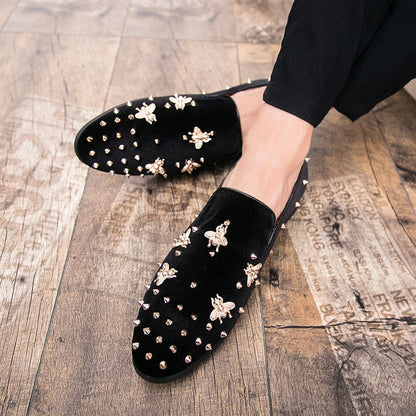 Black velvet loafers adorned with gold bee embroidery and studded details.