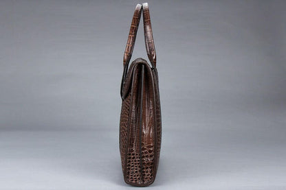 Brown crocodile leather handbag with structured shape and dual handles.