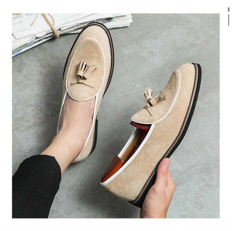 Pair of beige suede loafers with decorative tassels on the vamp.