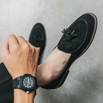 Black suede loafer with a tassel detail.