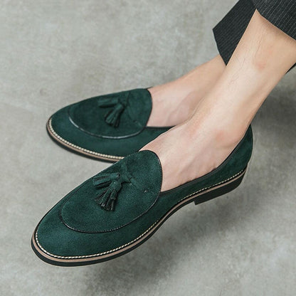 Dark green suede loafers with tassels and contrasting light-colored soles.