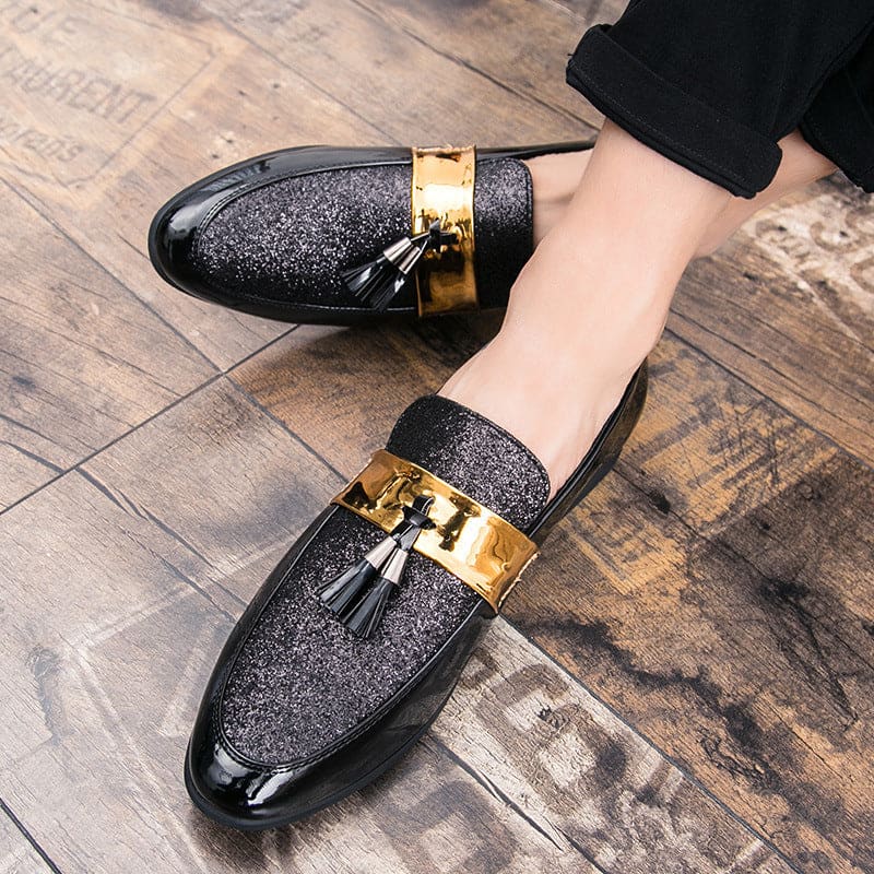 Glittery black loafers with gold metallic straps and tassels.