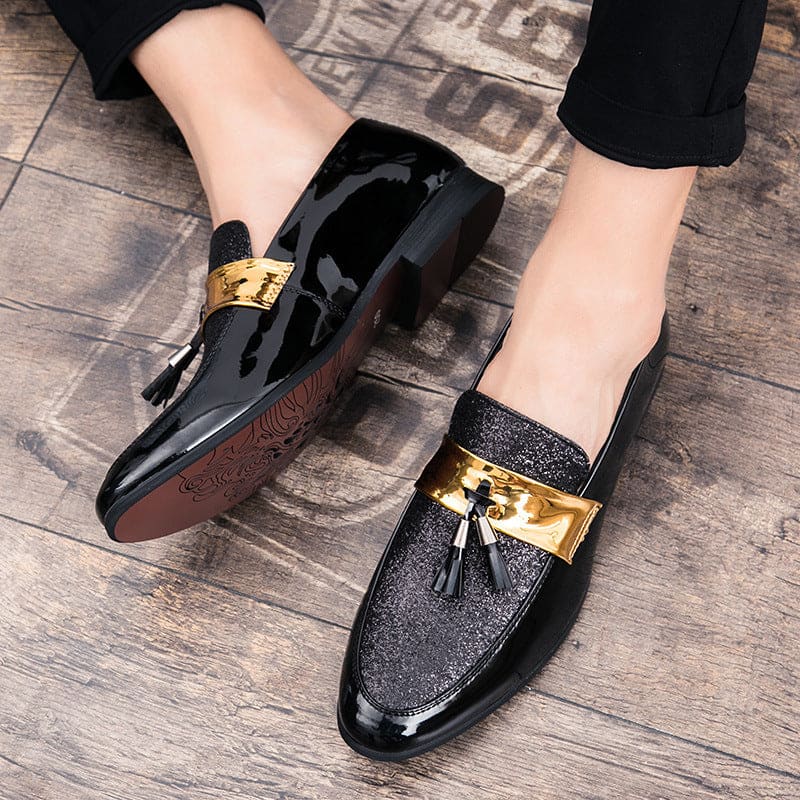 Stylish black loafers with gold accents and tassels.