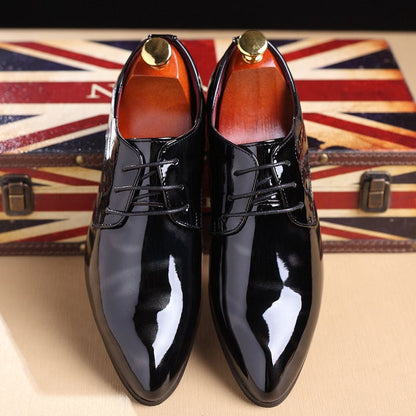 Pair of glossy black patent leather dress shoes with laces.