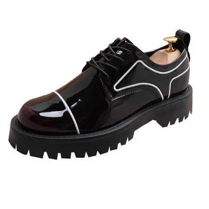 Black patent leather platform shoe with chunky sole and white trim detailing.