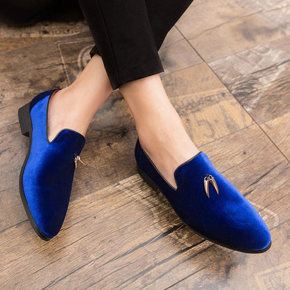 Pair of vibrant blue velvet loafers with metallic accents.