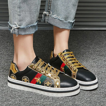 Stylish sneakers with black leather, gold accents, and colorful embroidered designs.