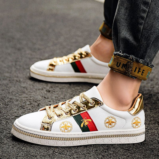 White sneaker with gold accents, red and green stripes, and floral embroidery.