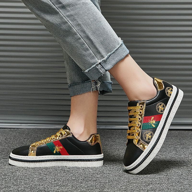 Stylish black sneakers with gold accents and colorful embroidered designs.