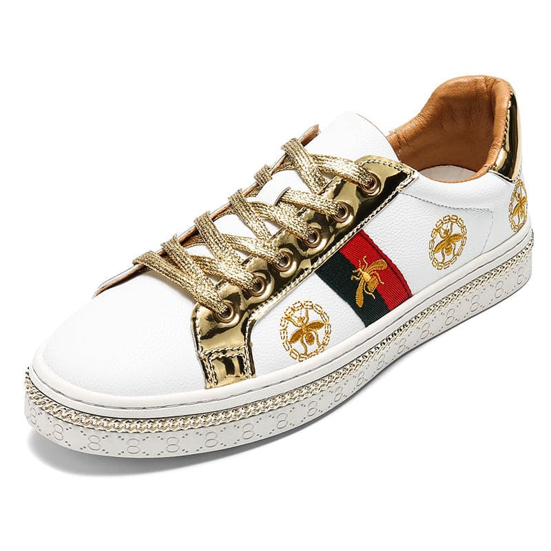 White leather sneaker with gold laces and decorative red and green stripe.