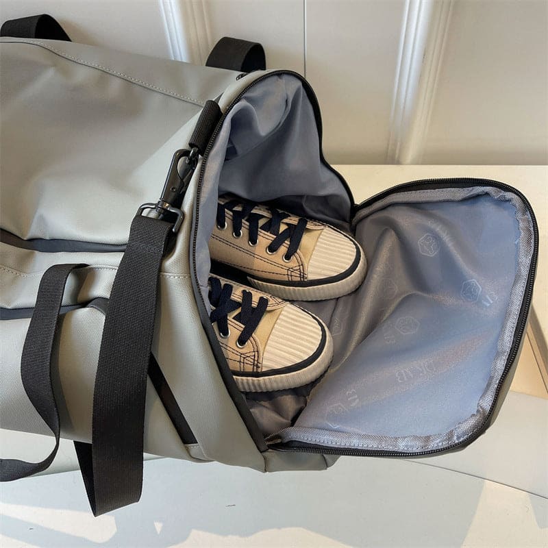 Open duffel bag containing a pair of beige sneakers with black laces.