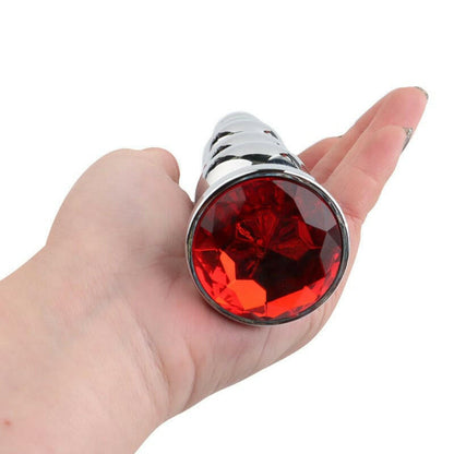 Metal anal plug with a large red jewel on the end.