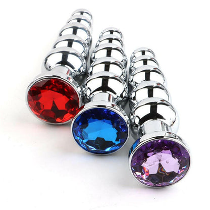 Metal anal plugs with colorful jeweled bases in red, blue, and purple.