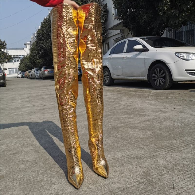 Pair of shiny gold thigh-high boots with pointed toes.