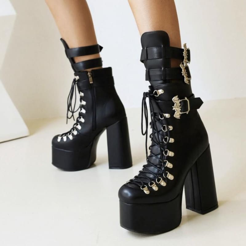 Pair of black platform boots with chunky heels, laces, and decorative buckles.