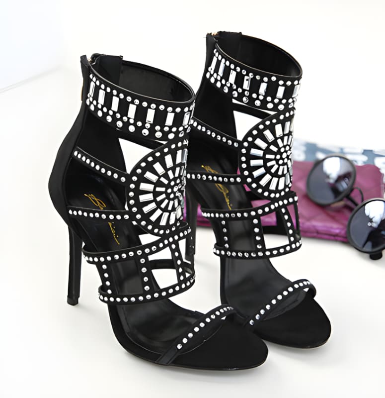 Pair of black high-heeled sandals with intricate white beaded patterns.