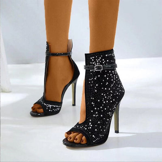 Sparkly black high-heeled sandals with open toes and ankle straps.