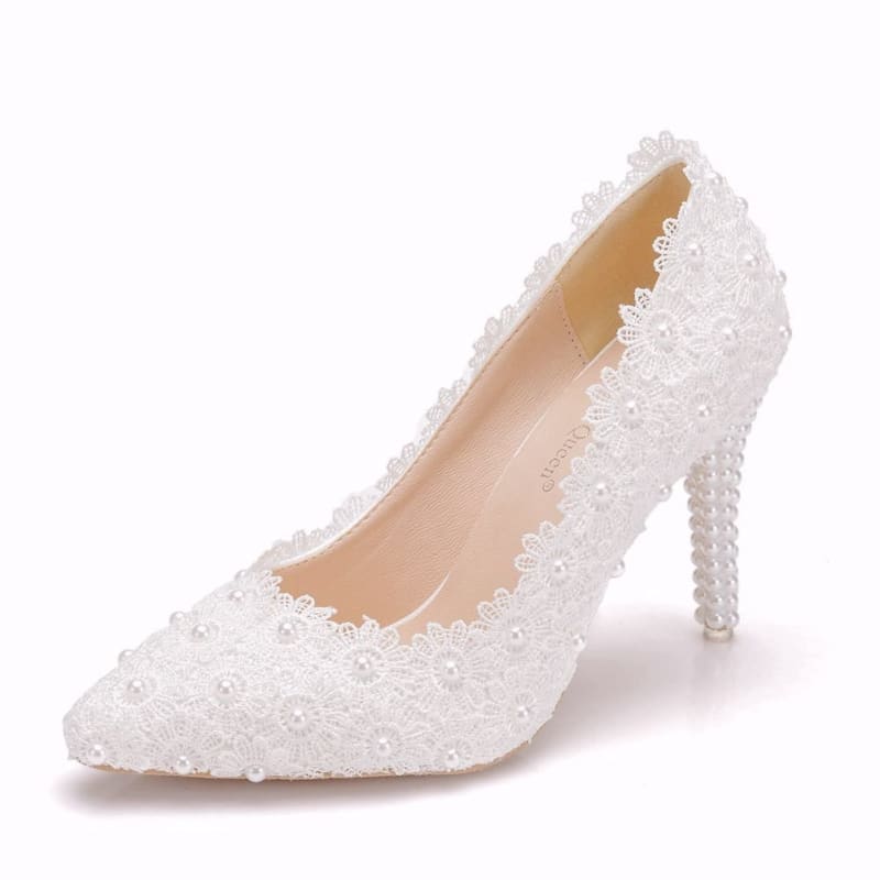 Elegant white high-heeled shoe adorned with lace and pearl-like embellishments.