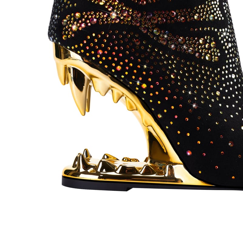 High-heeled shoe with a gold shark-tooth shaped sole and black sequined upper.