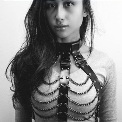 Leather harness with metal chains worn over a white top.