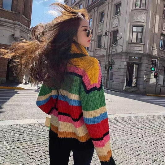 Colorful striped knit sweater worn by a woman with long, windblown hair.