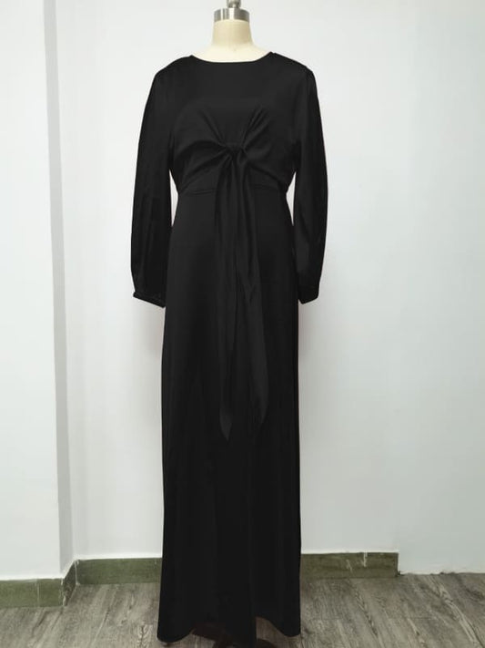 Long black dress with long sleeves and a bow detail at the waist.