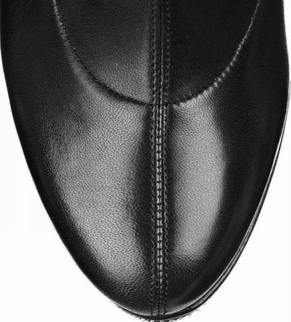 Black leather shoe with a pointed toe and visible stitching.