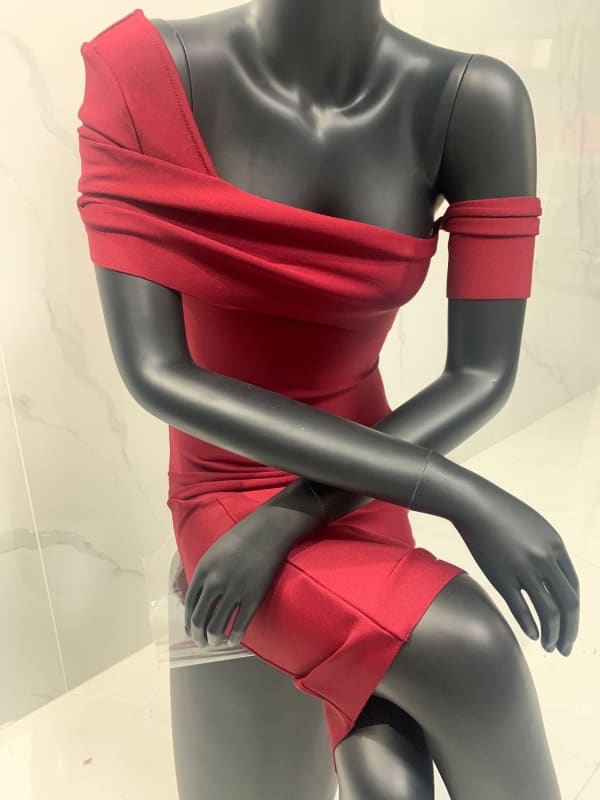 Mannequin torso wearing a form-fitting red dress or top with an asymmetrical neckline.