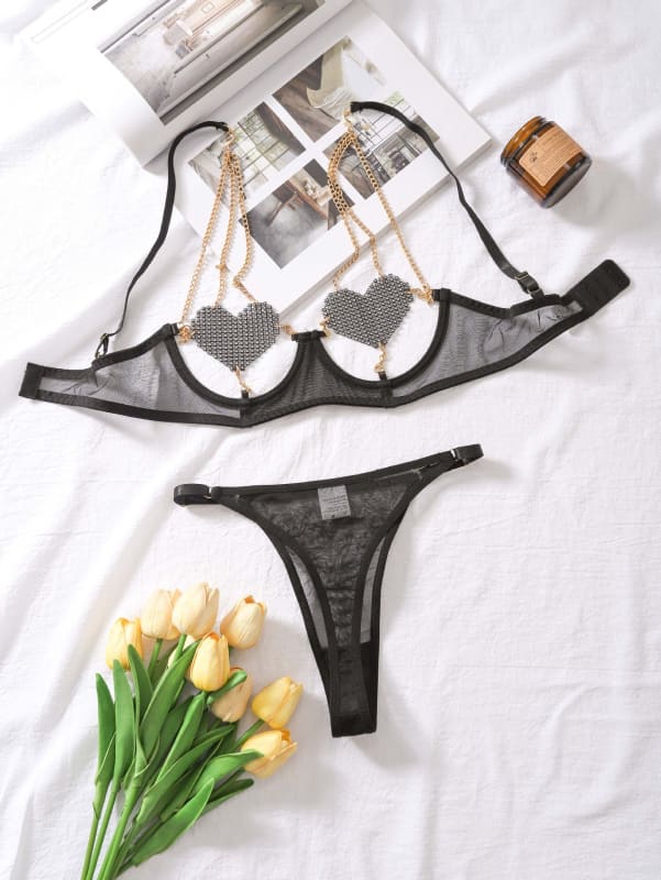 Black mesh lingerie set consisting of a bra and thong with heart-shaped decorative elements.