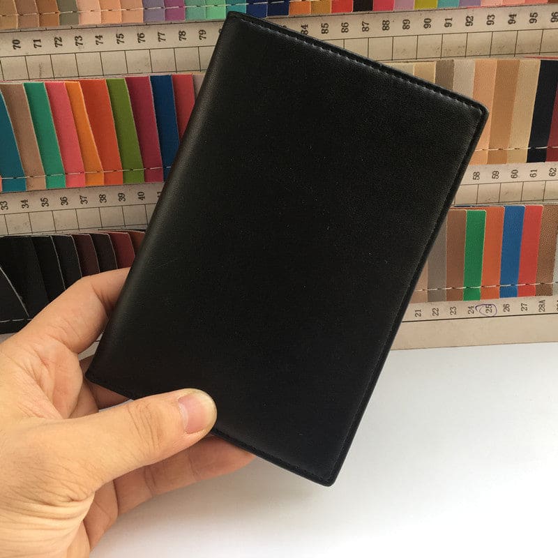 Black leather passport holder or travel wallet held in a hand.