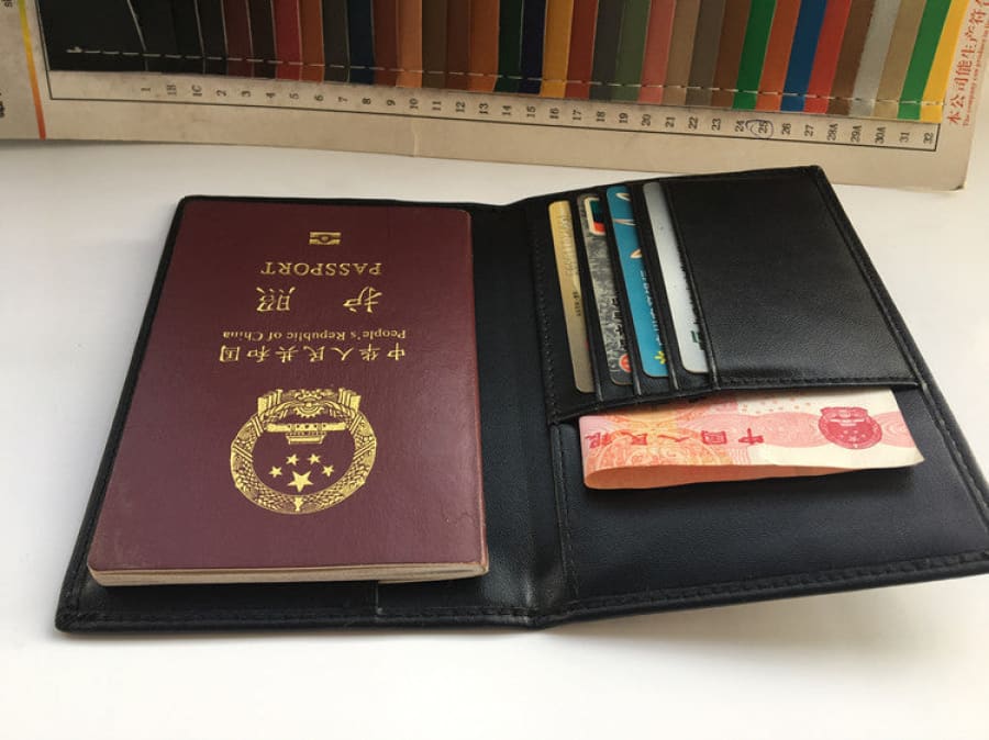 Burgundy passport with gold emblem alongside a black wallet containing cards and currency.