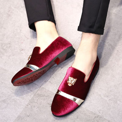 Pair of burgundy velvet loafers with decorative gold accents.