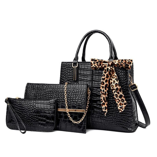 Black crocodile-textured handbag with leopard print scarf accent, accompanied by matching wallet and clutch.