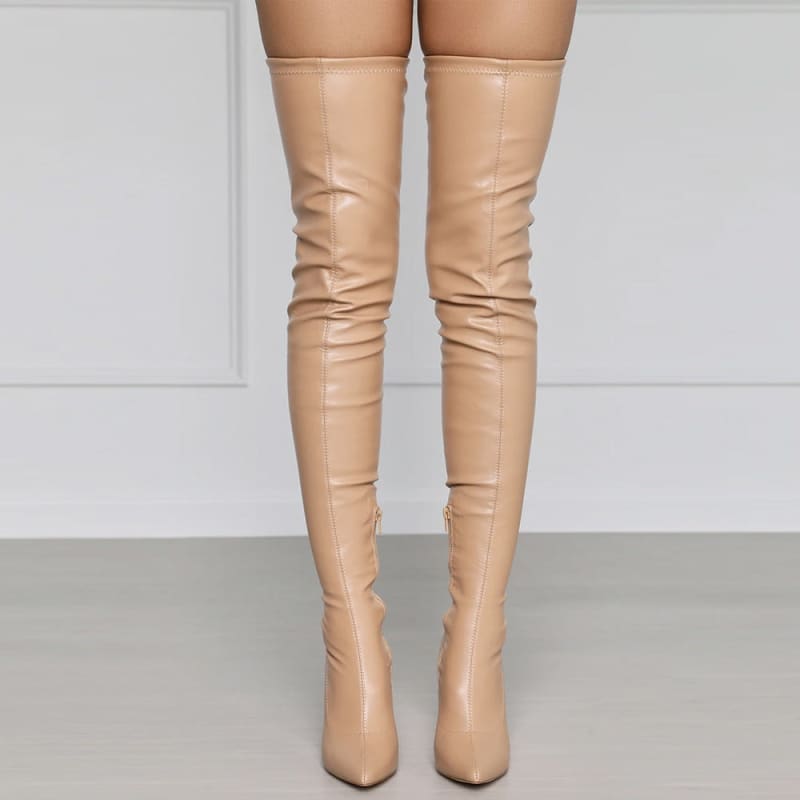 Pair of nude-colored thigh-high leather boots with pointed toes and stiletto heels.