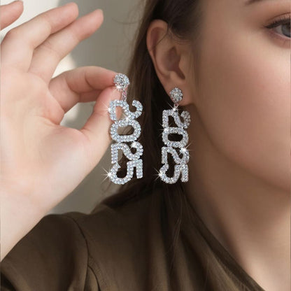 Sparkling diamond-encrusted earrings spelling out ’DRUG’ in dangling letters.