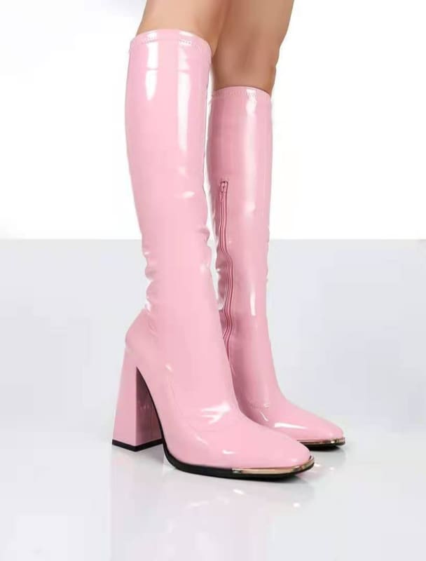 Pair of shiny pink knee-high boots with chunky heels.