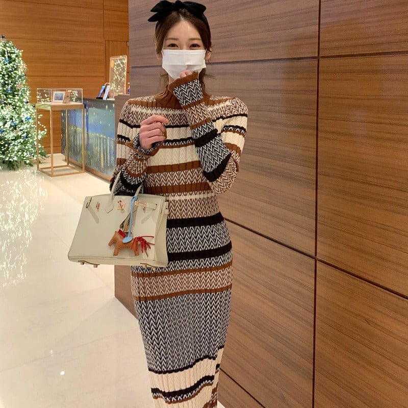 Woman wearing a patterned knit dress and face mask, holding a handbag.