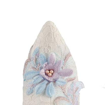 Lace-covered pointed object with a delicate pastel flower decoration.