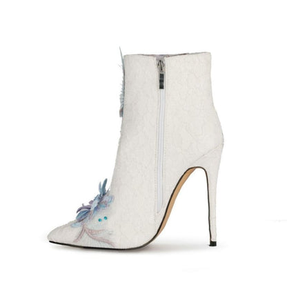 White high-heeled ankle boot with a blue floral embellishment on the toe.