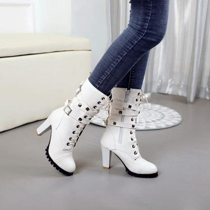 White high-heeled ankle boots with studs and buckle straps.