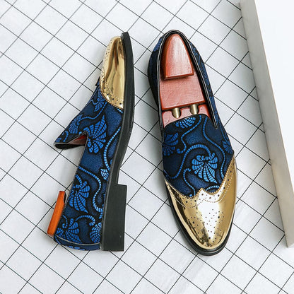 Stylish men’s loafers with gold toe caps and blue floral embroidery on navy fabric.