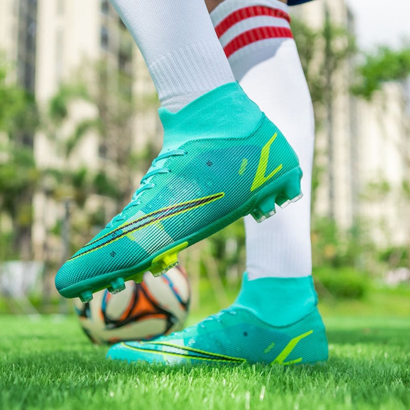 Bright turquoise soccer cleats with yellow accents on a player’s feet touching a soccer ball.