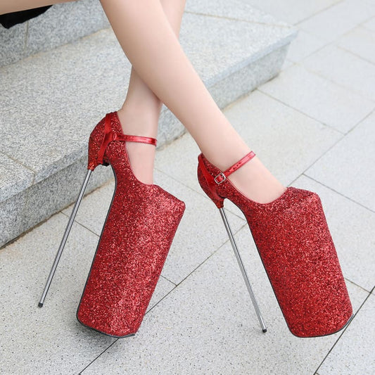 Pair of extremely high platform stiletto shoes in glittery red with ankle straps and metallic spike heels.