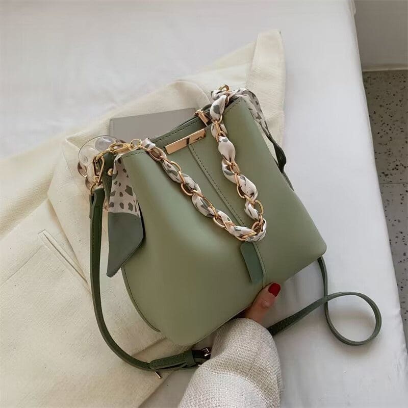 Sage green handbag with a decorative shell chain handle.