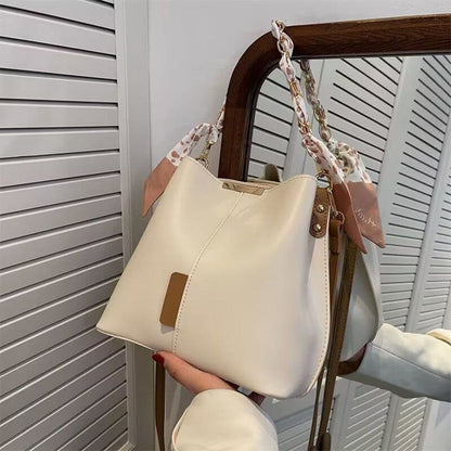 Cream-colored handbag with brown leather trim and a patterned fabric strap.