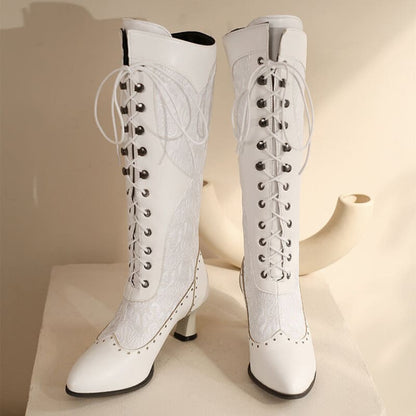 Pair of white knee-high lace-up boots with pointed toes and heels.