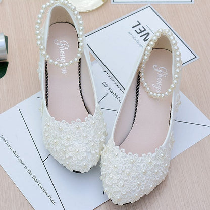 Pair of white bridal shoes adorned with pearls and lace detailing.