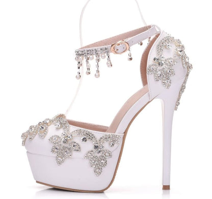 Ornate white high-heeled shoe with crystal embellishments and ankle strap.