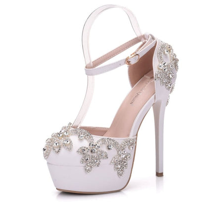 Ornate white high-heeled shoe with crystal embellishments and an ankle strap.