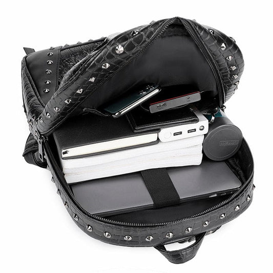 Black studded backpack with electronic devices visible inside its open compartment.